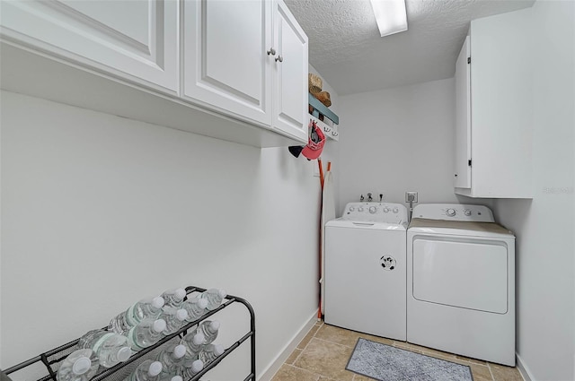 clothes washing area featuring washing machine and dryer, cabinets, and a textured ceiling