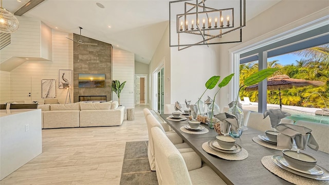 dining room featuring beamed ceiling, high vaulted ceiling, and a tiled fireplace