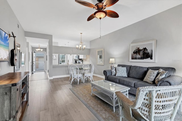 living room featuring ceiling fan with notable chandelier and hardwood / wood-style flooring