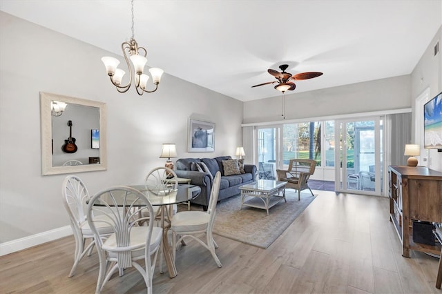 dining space with ceiling fan with notable chandelier and light hardwood / wood-style flooring