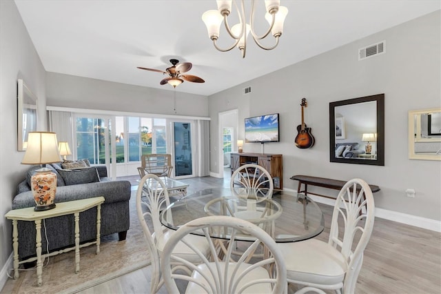 dining room with ceiling fan with notable chandelier, light wood-type flooring, and a wealth of natural light