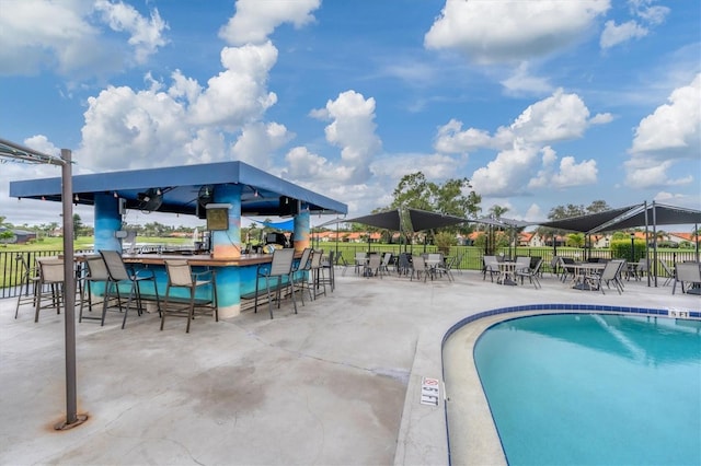 view of swimming pool with an outdoor bar and a patio