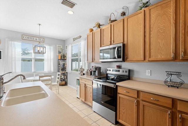 kitchen featuring pendant lighting, light tile patterned floors, sink, and appliances with stainless steel finishes