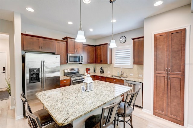 kitchen with sink, a breakfast bar area, decorative light fixtures, a kitchen island, and stainless steel appliances