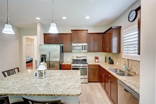 kitchen featuring a breakfast bar area, sink, pendant lighting, and appliances with stainless steel finishes