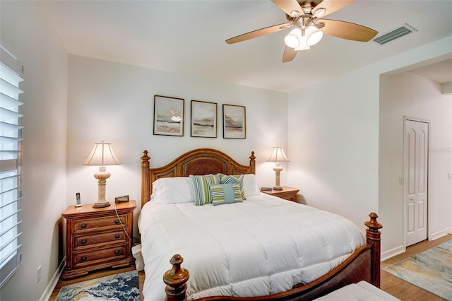 bedroom with multiple windows, wood-type flooring, a closet, and ceiling fan