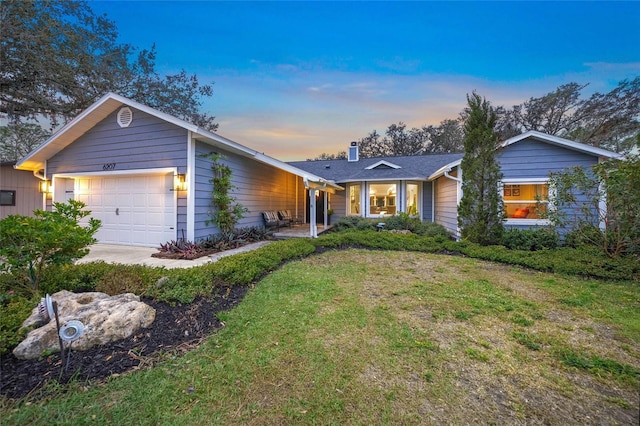 ranch-style home with a garage and a lawn