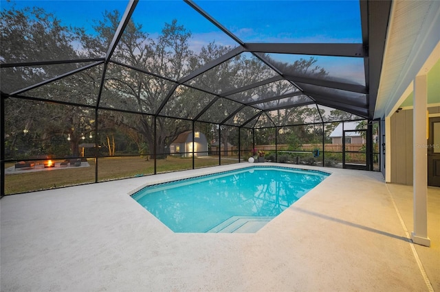 pool at dusk with a lawn, glass enclosure, and a patio area