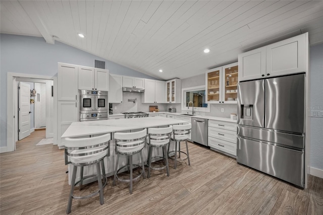 kitchen featuring stainless steel appliances, wooden ceiling, a kitchen bar, and decorative backsplash