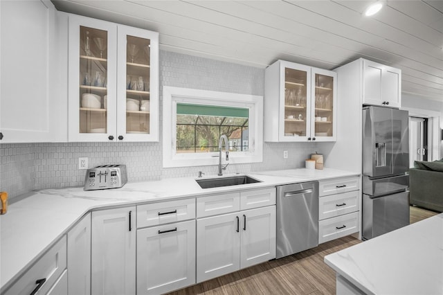 kitchen with white cabinetry, sink, decorative backsplash, light stone counters, and stainless steel appliances