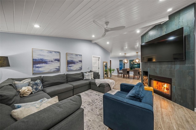 living room with lofted ceiling, wood ceiling, a tile fireplace, ceiling fan, and hardwood / wood-style floors