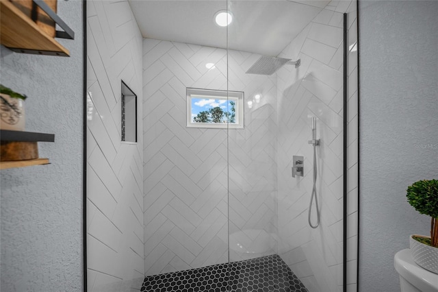 bathroom with tiled shower and toilet