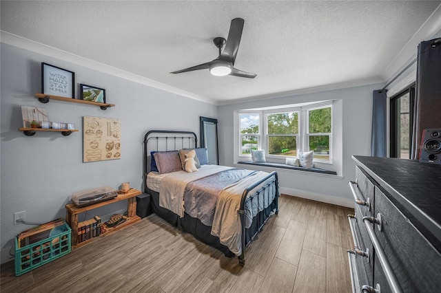 bedroom featuring a textured ceiling, wood-type flooring, ornamental molding, and ceiling fan