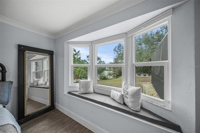 living area with ornamental molding, plenty of natural light, and dark wood-type flooring