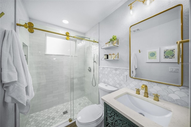 bathroom with tile walls, vanity, a shower with door, and toilet