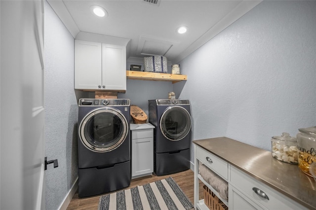 laundry area featuring crown molding, cabinets, light hardwood / wood-style floors, and washer and dryer