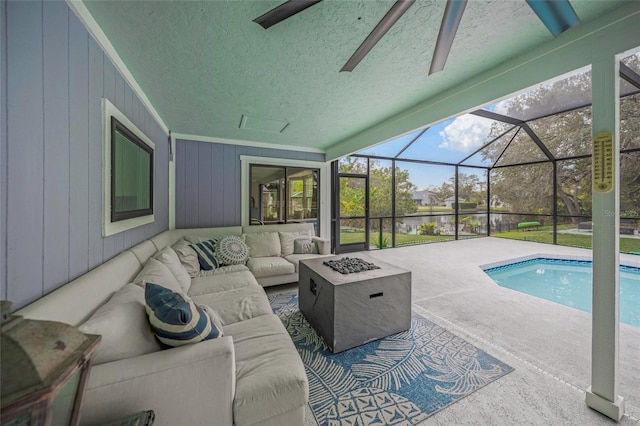 view of swimming pool with a lanai, a patio area, and an outdoor living space with a fire pit