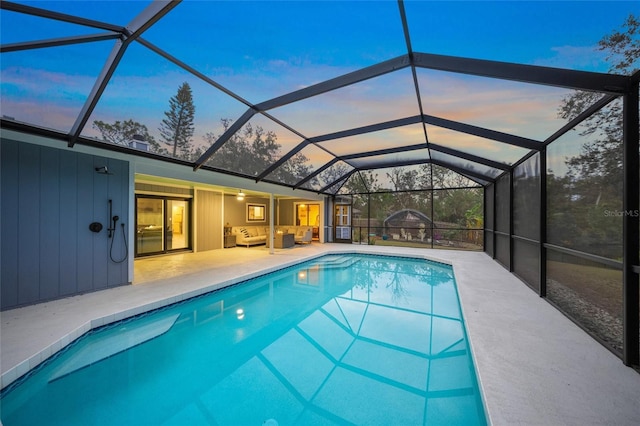 pool at dusk featuring a lanai, an outdoor hangout area, and a patio