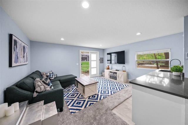 carpeted living room featuring sink, a wealth of natural light, and a textured ceiling