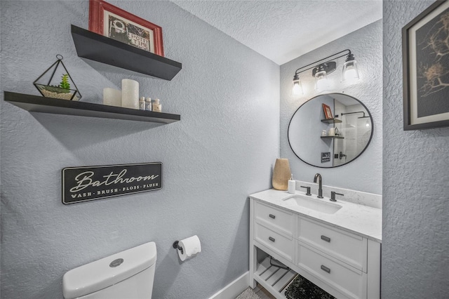 bathroom with vanity, toilet, and a textured ceiling