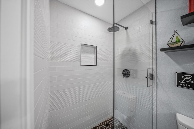 bathroom featuring a tile shower and toilet