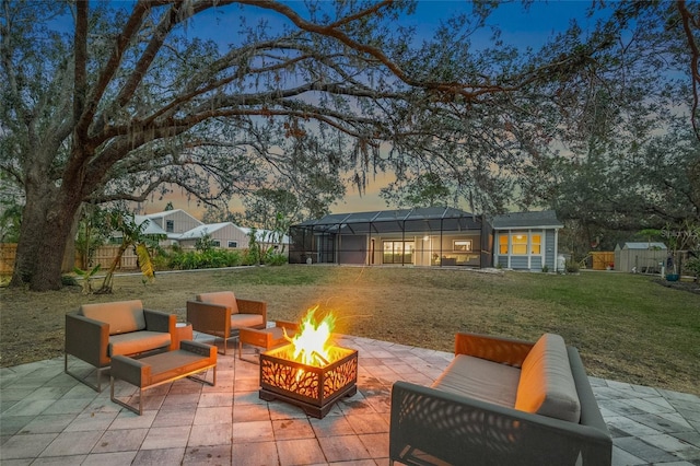 patio terrace at dusk with glass enclosure, an outdoor fire pit, a yard, a storage unit, and a playground