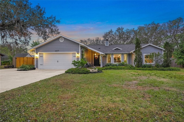 ranch-style home with a garage and a lawn