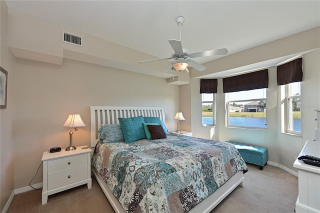 carpeted bedroom with multiple windows, a water view, and ceiling fan