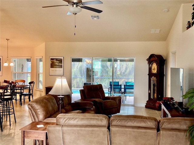 tiled living room with ceiling fan with notable chandelier and vaulted ceiling