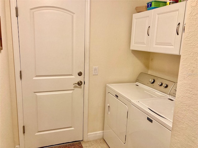 washroom featuring washing machine and clothes dryer, light tile patterned flooring, and cabinets