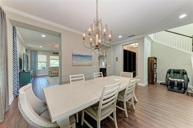 dining room with a textured ceiling, a notable chandelier, wood-type flooring, and ornamental molding