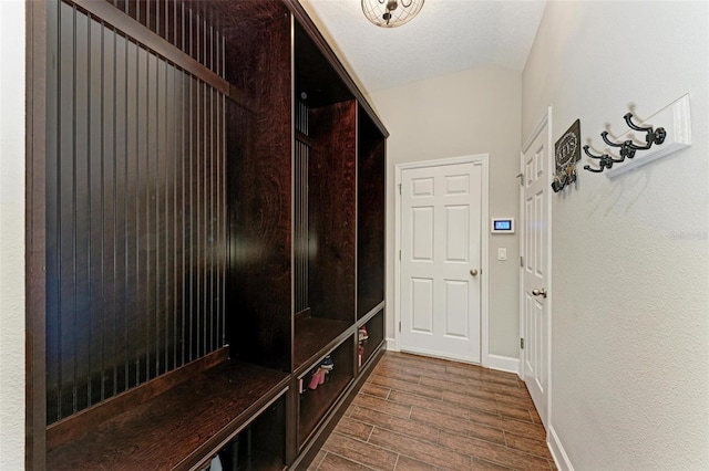 mudroom with a textured ceiling, vaulted ceiling, baseboards, and wood tiled floor