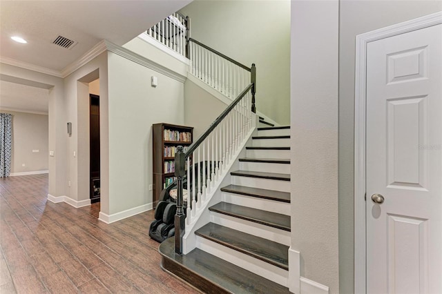 stairs with hardwood / wood-style floors and ornamental molding