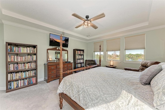 carpeted bedroom with a ceiling fan, a raised ceiling, baseboards, and ornamental molding