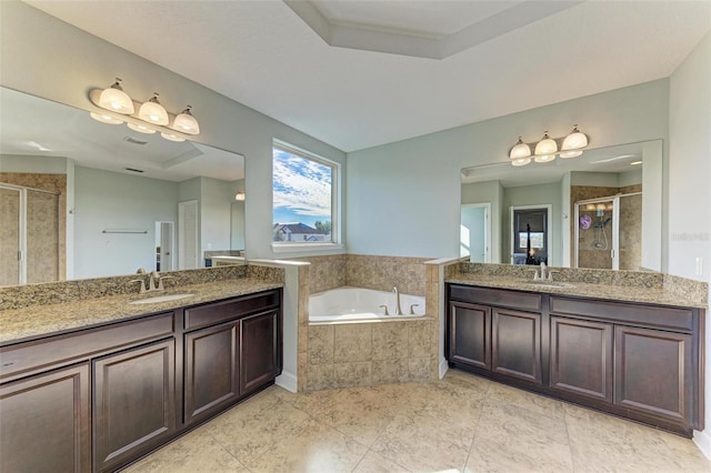 full bath featuring a stall shower, two vanities, a garden tub, and a sink