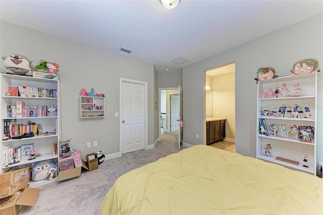 carpeted bedroom with a textured ceiling and ensuite bathroom