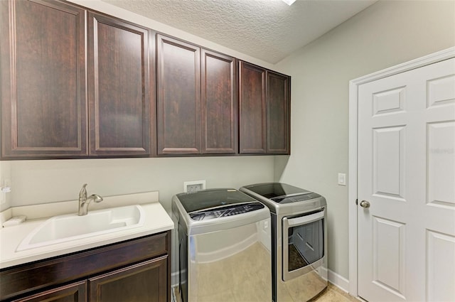 laundry room featuring washing machine and clothes dryer, baseboards, cabinet space, a textured ceiling, and a sink