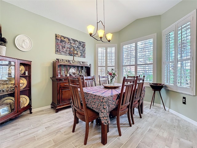 dining space with light wood-style floors, vaulted ceiling, baseboards, and an inviting chandelier