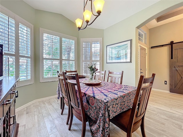 dining area featuring lofted ceiling, light wood-style floors, a barn door, and arched walkways