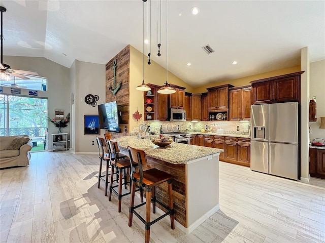 kitchen featuring visible vents, a peninsula, light stone countertops, stainless steel appliances, and open shelves