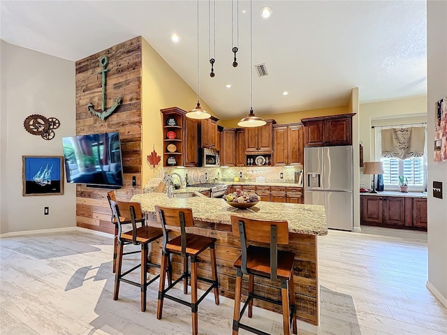 kitchen featuring tasteful backsplash, light stone counters, a peninsula, stainless steel appliances, and open shelves