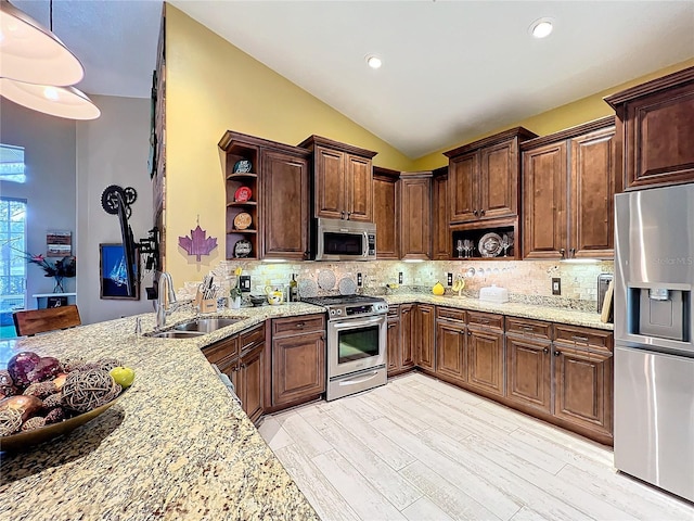 kitchen featuring light stone counters, open shelves, tasteful backsplash, appliances with stainless steel finishes, and a sink