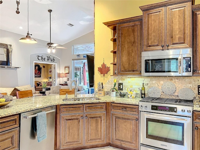 kitchen featuring stainless steel appliances, visible vents, open floor plan, a sink, and light stone countertops