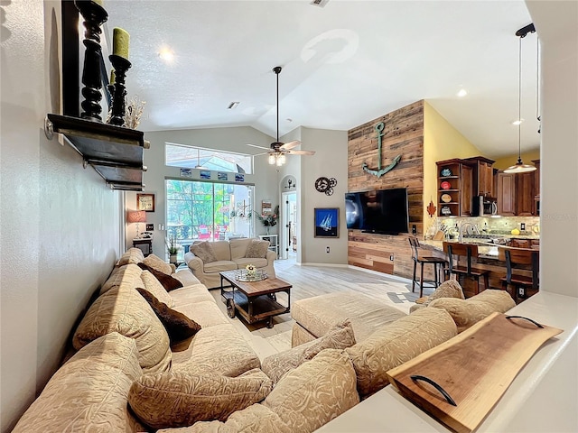 living area with high vaulted ceiling, light wood-type flooring, and a ceiling fan