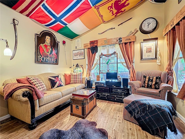 living area with vaulted ceiling, baseboards, and wood finished floors