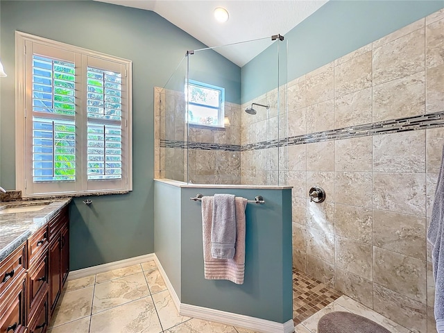 full bathroom featuring lofted ceiling, walk in shower, vanity, and baseboards