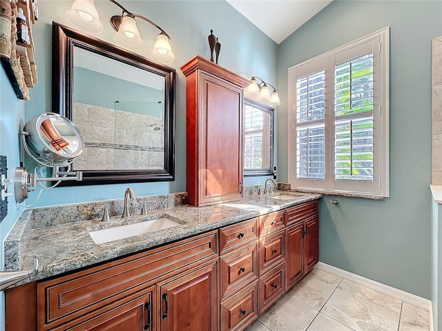 bathroom with lofted ceiling, a sink, baseboards, and double vanity