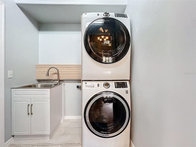 washroom with a sink, marble finish floor, cabinet space, and stacked washer / dryer