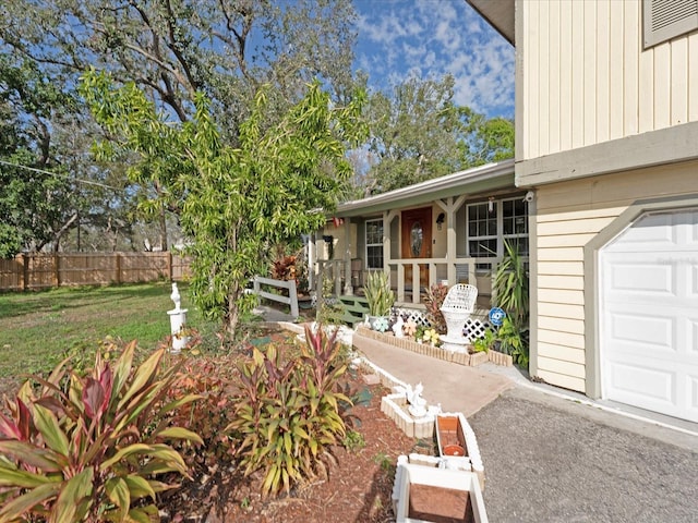 exterior space featuring a garage, covered porch, and a lawn