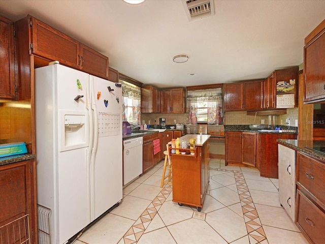 kitchen with backsplash, white appliances, a kitchen island, and light tile patterned floors